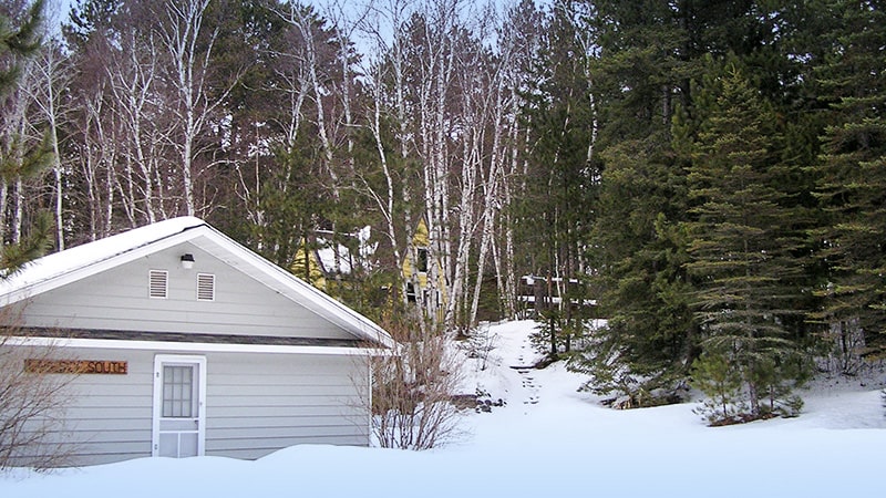 Lakeside cabin in winter covered with snow